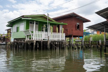 Chao Phraya nehrinin uzun kuyruklu ahşap botları ve Bangkok Tayland Asya 'daki konut binaları olan klong veya nehir kanalı.