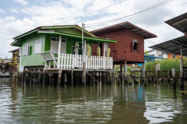 Chao Phraya nehrinin uzun kuyruklu ahşap botları ve Bangkok Tayland Asya 'daki konut binaları olan klong veya nehir kanalı.