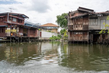 Chao Phraya nehrinin uzun kuyruklu ahşap botları ve Bangkok Tayland Asya 'daki konut binaları olan klong veya nehir kanalı.
