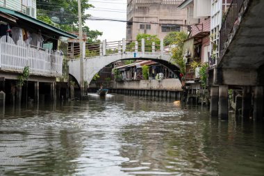 Chao Phraya nehrinin uzun kuyruklu ahşap botları ve Bangkok Tayland Asya 'daki konut binaları olan klong veya nehir kanalı.