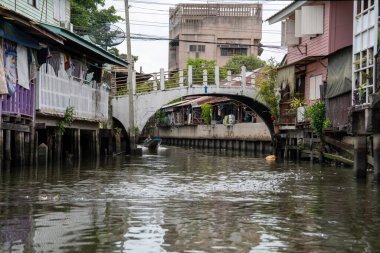 Chao Phraya nehrinin uzun kuyruklu ahşap botları ve Bangkok Tayland Asya 'daki konut binaları olan klong veya nehir kanalı.