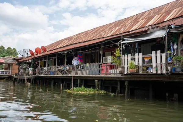 Chao Phraya nehrinin uzun kuyruklu ahşap botları ve Bangkok Tayland Asya 'daki konut binaları olan klong veya nehir kanalı.