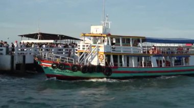 Tayland körfezi dalgalar yaratırken, turistler veya yolcular feribotla bir rıhtımdan bir adaya taşınıyor. Pattaya Chonburi bölgesi Tayland ve Asya