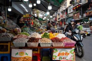Vietnamlı bir kadın, Vietnam 'da, Hanoi' nin eski mahallesindeki bir sokak dükkanında motosikletli bir müşterisiyle tezgahtar olarak çalışıyor..