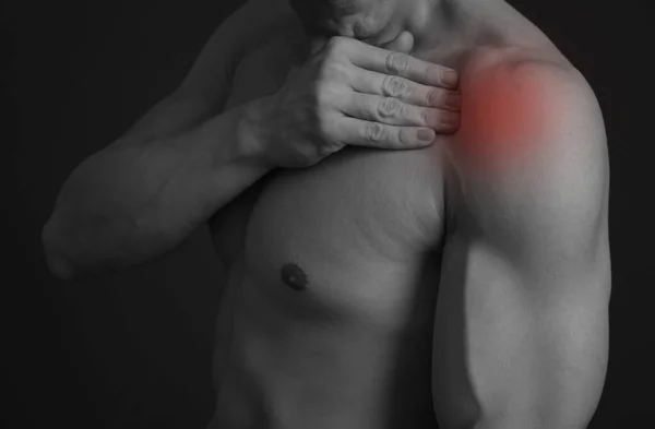 Muscular man with shoulder pain. Sport exercising injury