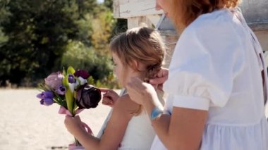 Beyaz elbiseli anne ve kızı kumsalda birlikte vakit geçirip eğleniyorlar. Yüksek kalite 4k görüntü