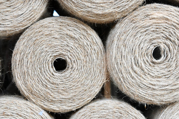 Large spools of twine, handmade skeins of rope, gray thread close-up.