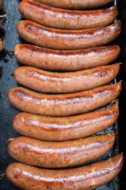 Izgarada ızgara sosis, arka planda sokak yemeği, kızarmış sosis..