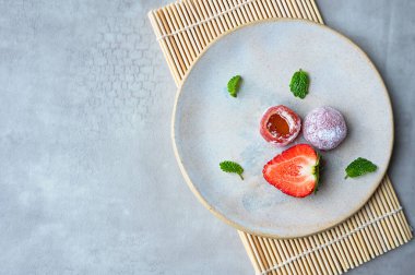 Mochi ve çilekli tabak ve ahşap hasırın üzerinde nane yaprağı, Japon geleneksel pirinç keki..