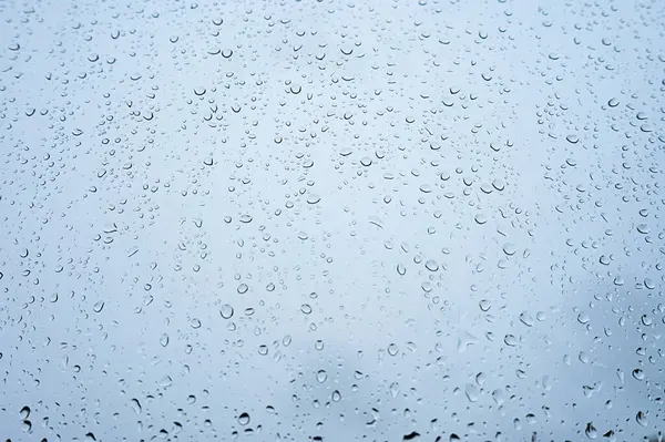 Penceredeki yağmur damlalarının arka planı, su damlaları deseni, yağmur havası.