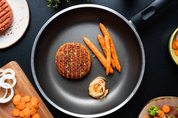 Frying pan with grilled vegan plant-based meat and carrots, lunch from meatless healthy food.
