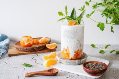 Yoğurt ya da hindistan cevizi sütü beyaz arka planda chia tohumu ve clementine, kahvaltıda sağlıklı puding..