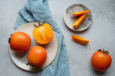 Gri arkaplanda tekstil içeren hurma eriği ya da Sharon Hurma meyvesi ve takozları.