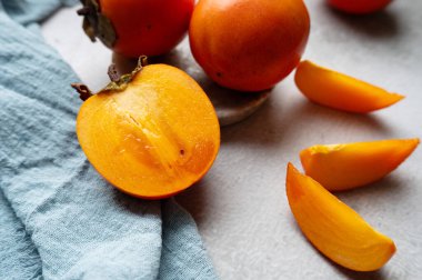 Olgun Sharon hurmasının yarısının yakın plan çekimi ve gri arka planda dilimler.