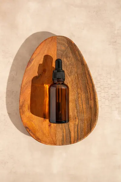 Kozmetik şişesinde yüz serumu, ahşap bir tabakta gerekli yağ veya retinol, doğal bakım, üst görünüm..