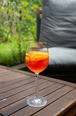 Bahçedeki ahşap masada şarap kadehinde Aperol spritz kokteyli..