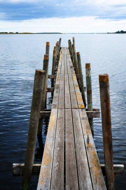 İskele tahtalardan inşa edilmiş, eski ahşap iskele bir göl veya nehirde, kötü bir gün..