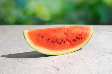 Sulu karpuz dilimi açık havada yeşil arka planda, yaz meyveleri.
