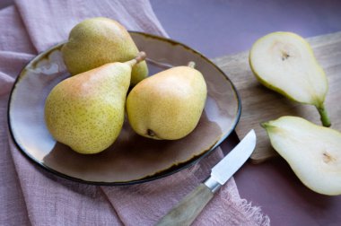 Bütün armutlar bir tabağı süslüyor, yanında sulu, taze kesilmiş yarımlar var..