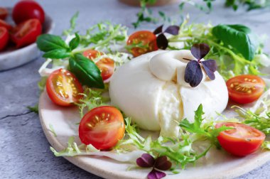Kremalı burrata peyniri, mozzarella ve taze kremadan yapılır, fesleğen yaprağı, marul ve domateslerle eşleştirilir..