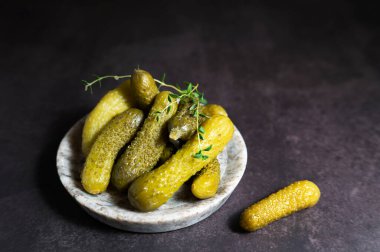 Salatalık turşusu ve turşuyla dolu bir tabağın yakın plan fotoğrafı. Sağlıklı yaşam için siyah bir zemin, mayalanmış, probiyotik zengini gıdaların üzerine yerleştirilmiş..