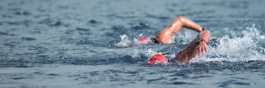 Triatlon yüzücüleri suda çalkalanıyor. Triatlonda yarışan iki yüzücü.