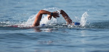 Triatlon yüzücüleri, triatlonda yarışan iki yüzücüyü suda çalkalayıp dururlar.