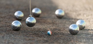 Magnetic pick-up tool for petanque. Petanque balls boules bowls on closeup on sand gravel court background, lifting the ball with a magnet