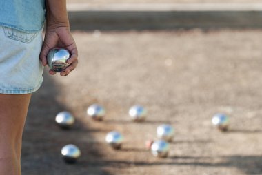 Senior playing petanque un and relaxing game, balls on the ground. Senior woman prepared to throw the boules ball in a park in outdoor play