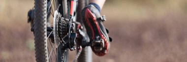 Mountain biker riding on bike singletrack trail, back view of mountain biker. Focus on the gears and rear derailleur . Mountain bike race
