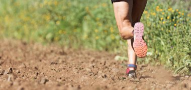 Spor yapan, spor yapan, spor yapan, sahayı tarlaya süren, spor ayakkabılarına yakın çekim yapan bir sporcu.