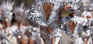 Renkli kostümler içinde dans eden bir grup karnaval için geleneksel bir dans gösterisi düzenliyor.