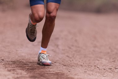 Yaz aylarında dağlarda koşan patika koşucusu dağlarda zorlu bir yolda, ormanda tozlu bir ortamda koşuyor.