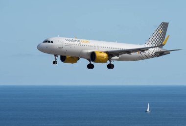 Tenerife, İspanya 4 Haziran 2023. Vueling Airlines Airbus a320 Tenerife Uluslararası Havaalanına iniyor. Vueling Havayolları okyanusun üzerinde mavi gökyüzünde uçuyor.