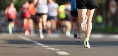 Şehir yolunda koşan maraton koşucuları, büyük bir koşucu grubu, spor maratonu koşan yakın mesafe koşucuları, asfalt yolda koşan erkek koşucular, atletizm yarışması