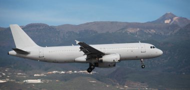 Uçak pistleri. Uçak, gökyüzünde uçan yolcular, havaalanına inmeye hazırlanıyorlar. Arka planda El Teide volkanı