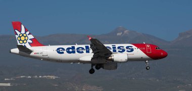 Tenerife, İspanya 15 Aralık 2023. Airbus A320-214 Edelweiss Hava Yolları mavi gökyüzünde uçuyor. Tenerife Havaalanına iniyor. Arka planda El Teide volkanı