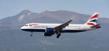 Tenerife, İspanya 13 Ocak 2024. Airbus A320-251N British Airways Airlines mavi gökyüzünde uçuyor. Tenerife Havaalanına iniyor. Arka planda El Teide volkanı