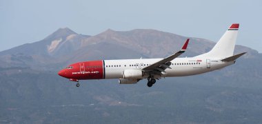 Tenerife, İspanya 13 Ocak 2024. Boeing 737-8JP Norveç Havayolları mavi gökyüzünde uçuyor. Tenerife Havaalanına iniyor. Arka planda El Teide volkanı