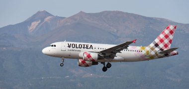 Tenerife, İspanya 13 Ocak 2024. Airbus A319-112 Volotea Havayolları mavi gökyüzünde uçuyor. Tenerife Havaalanına iniyor. Arka planda El Teide volkanı