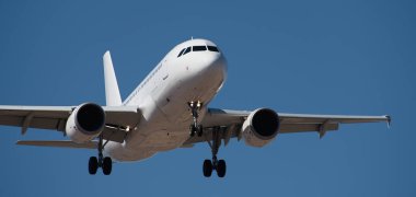 Uçak pistleri. Mavi gökyüzünde uçan yolcular, havaalanına inmeye hazırlanıyor.