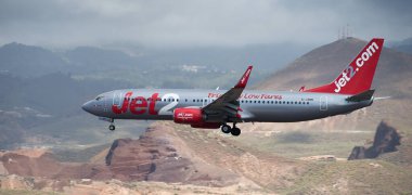 Tenerife, İspanya 31 Mart 2024. Boeing 737-8MG Jet2 Airlines bulutlarla mavi gökyüzünde uçuyor. Tenerife Havaalanına iniyor. Arkaplanda dağlar