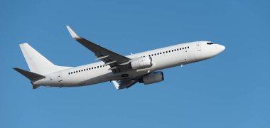 Mavi gökyüzünde uçak kalkıyor, gökyüzünde uçan uçak var. Mavi gökyüzünde beyaz yolcu uçağı. Mavi gökyüzünün altında uçan uçağın alçak açılı görüntüsü