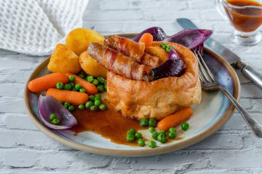 Toad in the hole with Yorkshire pudding, sausages and vegetables clipart