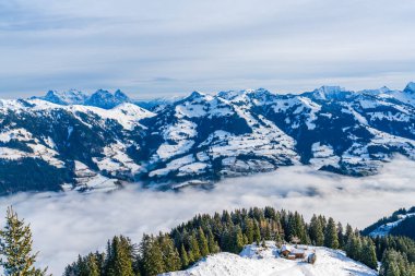 Panoramic aerial view of wintry landscape in Austrian Alps above low clouds covering Kitzbuhel in Austria
