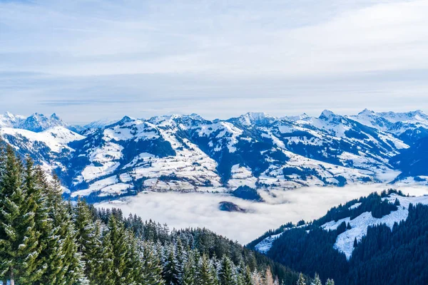 Panoramic aerial view of wintry landscape in Austrian Alps above low clouds covering Kitzbuhel in Austria