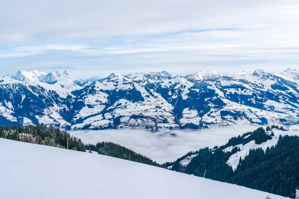 Panoramic aerial view of wintry landscape in Austrian Alps above low clouds covering Kitzbuhel in Austria
