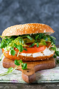 Vegetarian sesame bagel with cream cheese, tomato, avocado and watercress