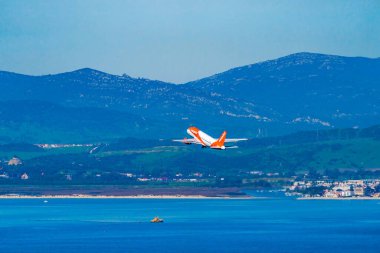 GIBRALTAR, İngiltere - 12 Mart 2023: EasyJet uçağı Cebelitarık Uluslararası Havalimanı 'ndan havalandıktan sonra denizin üzerinde uçar. Cebelitarık bir İngiliz Denizaşırı Toprakları.