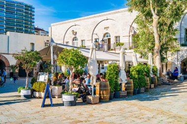 GIBRALTAR, İngiltere - 10 Mart 2023: Turistler Gibraltar kasabasındaki Casemates Meydanı 'nda güneşli havanın tadını çıkarıyorlar. Cebelitarık bir İngiliz Denizaşırı Toprakları ve popüler bir turizm beldesidir.